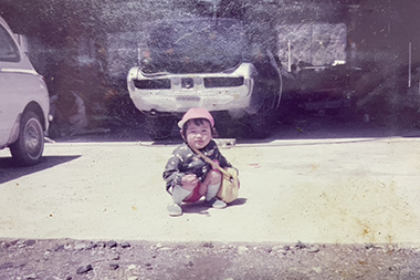 仕事場で遊ぶ現社長。後ろに年代物の車が見えます